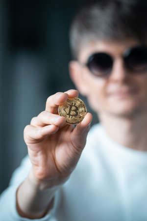 closeup of male investor holding golden bitcoin or cryptocurrency in handの写真素材