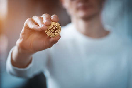 closeup of male investor holding golden bitcoin or cryptocurrency in handの写真素材