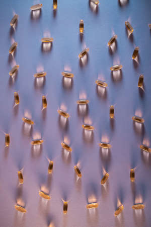 healthy golden fish oil capsules omega 3 vitamins on purple backgroundの写真素材