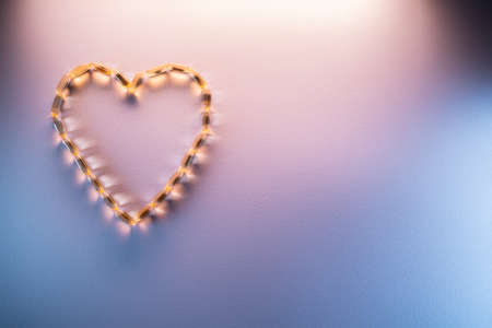 golden fish oil capsules omega 3 vitamins in heart shape on purple backgroundの写真素材