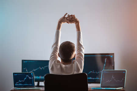 relaxed successful male trader resting with stock exchange graph or chartの写真素材