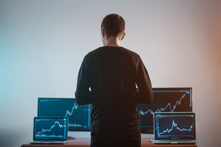 back view of male trader looking at monitor with stock exchange graph or chartの写真素材