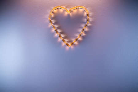 golden fish oil capsules omega 3 vitamins in heart shape on purple backgroundの写真素材