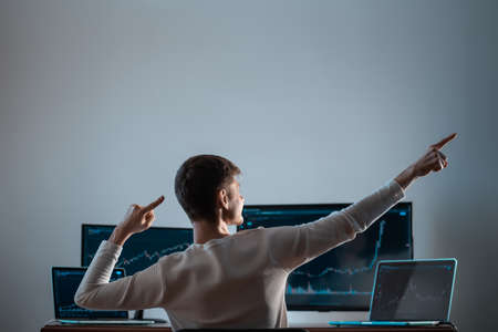 successful male trader looking at monitor with stock exchange graph or chartの写真素材