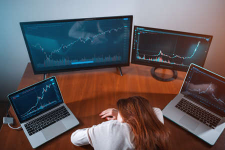 tired female beginner trader sleeping near monitor with stock chart at workplaceの写真素材