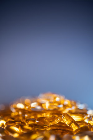 handful of golden fish oil capsules omega 3 vitamins on blue backgroundの写真素材