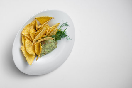 closeup of guacamole dip in bowl with avocado and nachos on white backgroundの写真素材