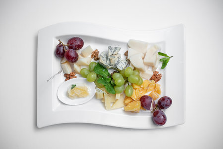 top view of cheese plate with grape, walnuts and honey on white backgroundの写真素材