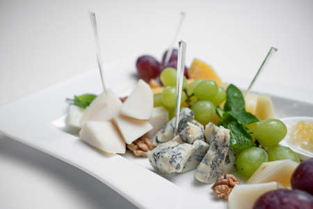 closeup of cheese plate with grape, walnuts and honey on white backgroundの写真素材