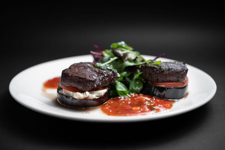 closeup of meat beef medallion on tomato and grilled eggplant with salsa sauce