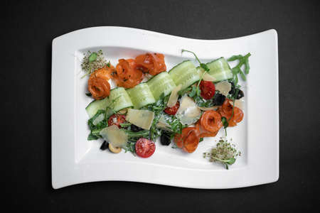 top view of salad with lightly salted salmon and vegetables on black backgroundの写真素材