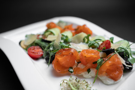 closeup of salad with lightly salted salmon and vegetables on black backgroundの写真素材