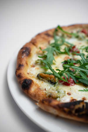 closeup of seafood pizza with shrimp, mussels and arugula on white backgroundの写真素材