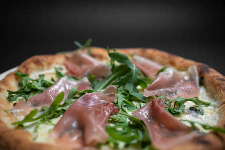 closeup of italian pizza with prosciutto, arugula and cheese on black backgroundの写真素材