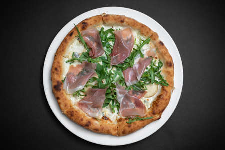 top view of pizza with prosciutto, arugula and cheese on black backgroundの写真素材