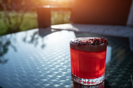 clover club cocktail drink with raspberry and rose petal outdoor at sunsetの写真素材