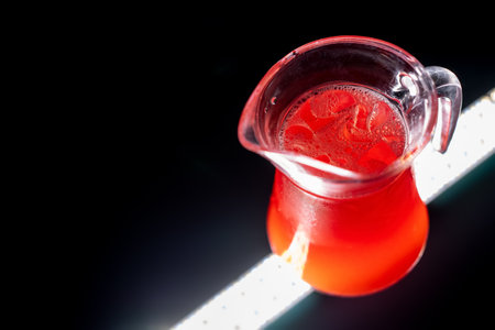 red berry lemonade or strawberry drink with ice in glass jug on black backgroundの写真素材