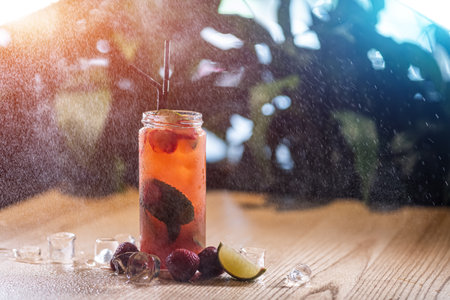 strawberry lemonade drink with mint and ice in glass bottle under water sprayの写真素材