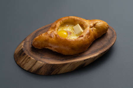 adjarian khachapuri with cheese and egg yolk on wooden board on grey backgroundの写真素材