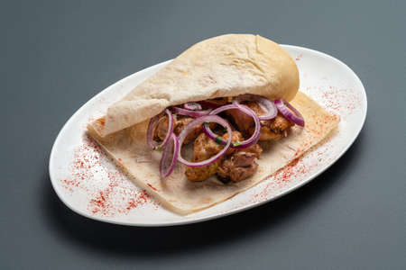 shashlik or grilled meat with onion in pita on white plate on grey backgroundの写真素材