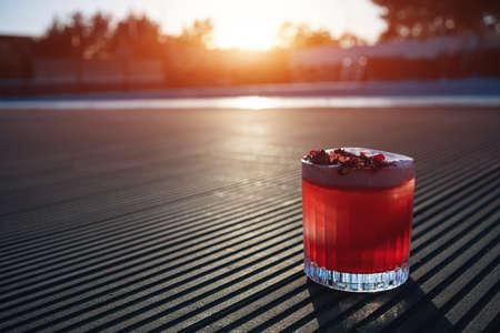 clover club cocktail drink with raspberry and rose petal outdoor at sunsetの写真素材