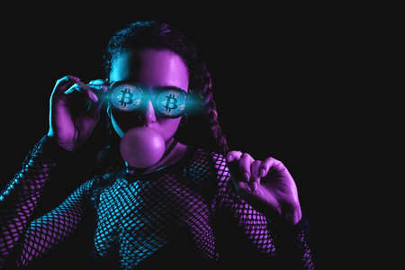 beautiful young cyberpunk female with bitcoin coin in eyes on neon backgroundの写真素材