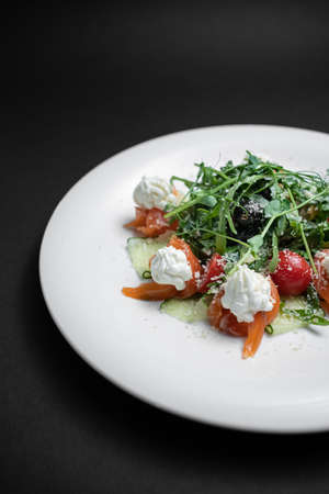 closeup of salad with salted salmon, cream cheese or arugula on black backgroundの写真素材