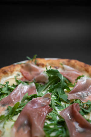closeup of italian pizza with prosciutto, arugula and cheese on black backgroundの写真素材