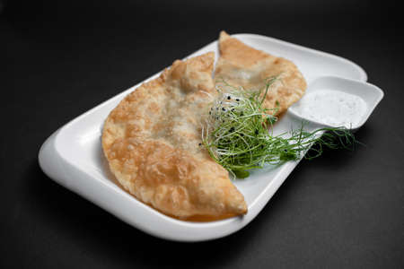 cheburek or fried dough pie with meat feeling and sauce on black backgroundの写真素材