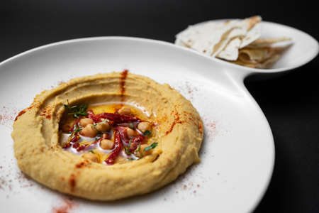 hummus with chickpea, olive oil, paprika and pita bread on black backgroundの写真素材