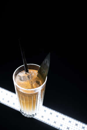refreshing lemonade drink or cocktail with ice cube in glass on black backgroundの写真素材