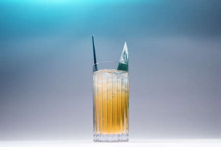 refreshing lemonade drink or cocktail with ice cube in glass on blue backgroundの写真素材
