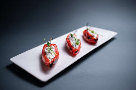 closeup of bulgarian peppers stuffed with cottage cheese on black backgroundの写真素材