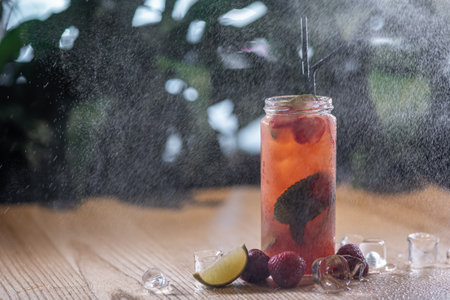 strawberry lemonade drink with mint and ice in glass bottle under water sprayの写真素材