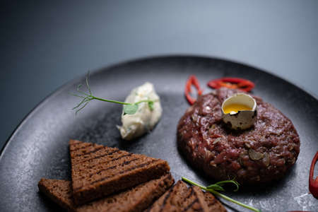 close up of beef steak tartare with raw egg yolk on plate on black backgroundの写真素材