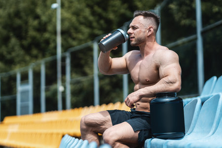 muscular athlete male drinking protein whey cocktail after exercising outdoorの写真素材
