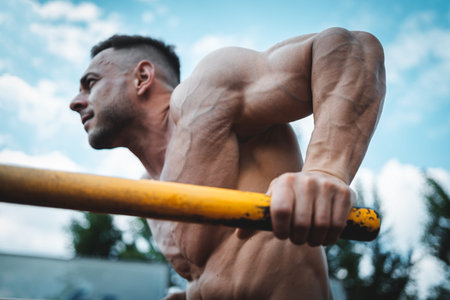 attractive muscular athlete man or bodybuilder pull up and exercising outdoor