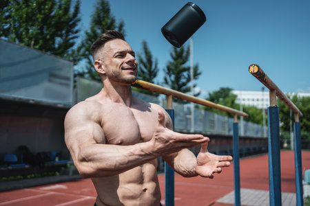 muscular athlete man throw up black container with protein whey powder outdoorの写真素材
