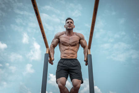 attractive muscular athlete man or bodybuilder pull up and exercising outdoorの写真素材