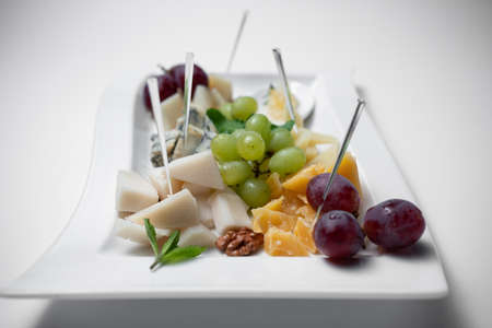 closeup of cheese plate with grape, walnuts and honey on white backgroundの写真素材