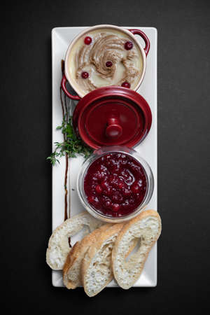 top view of goose meat liver pate with cranberry and bread on black backgroundの写真素材