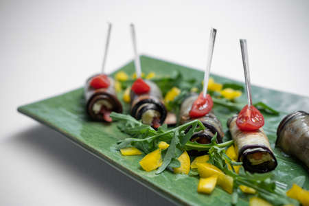 close up of eggplant rolls with cream cheese on green plate on white backgroundの写真素材