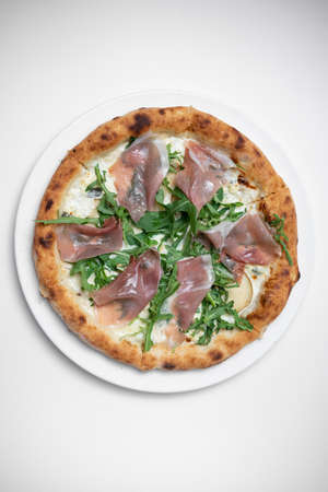 top view of tasty pizza with prosciutto, arugula and cheese on white backgroundの写真素材