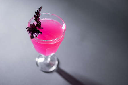 luxury alcohol pink cocktail drink with basil in glass on grey backgroundの写真素材