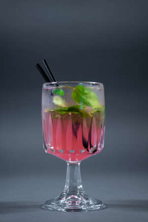 refreshing pink lemonade with mint or rose cocktail in glass on grey backgroundの写真素材