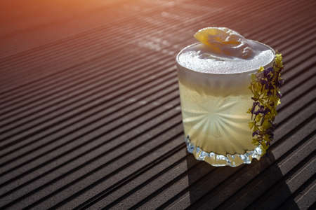 margarita pineapple cocktail in glass garnished flower on wooden backgroundの写真素材