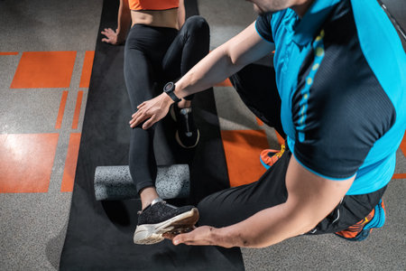 young female relaxing with myofascial release roller with trainer in gym