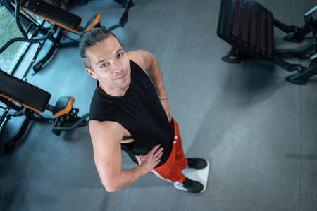 young attractive athlete male weight with scale in gym and dietingの写真素材