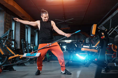 attractive male athlete cleaner have fun and dance and make cleaning in gymの写真素材