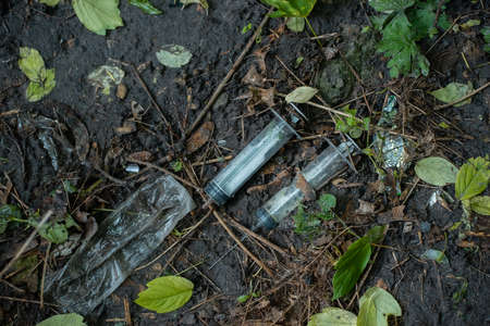 bunch of used dirty syringe leaved after drug injection lying on ground outdoorの写真素材